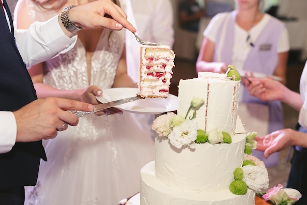 A noiva e o noivo cortam um lindo bolo de casamento em um banquete.