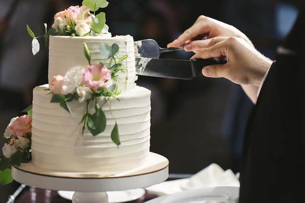 A noiva e o noivo cortam um lindo bolo de casamento em um banquete.