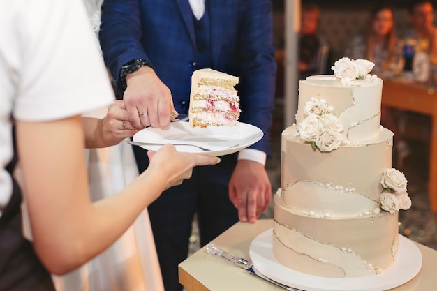 A noiva e o noivo cortam um lindo bolo de casamento em um banquete.