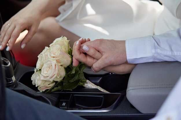 A noiva e o noivo de mãos dadas no carro com um buquê Um casamento elegante Dia do casamento Fotografia de história de amor Foto de alta qualidade