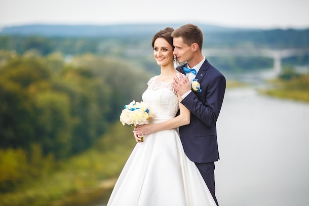A noiva e o noivo em um penhasco alto perto do rio Caminhe com os recém-casados Dia do casamento O melhor dia de um jovem casal