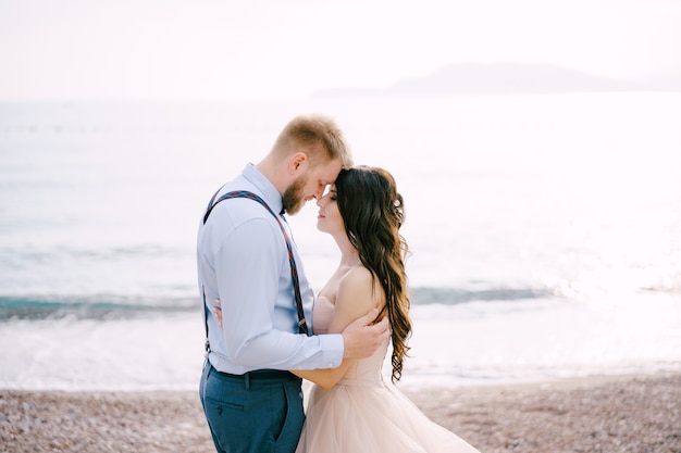 A noiva e o noivo ficam na praia de seixos e se abraçam