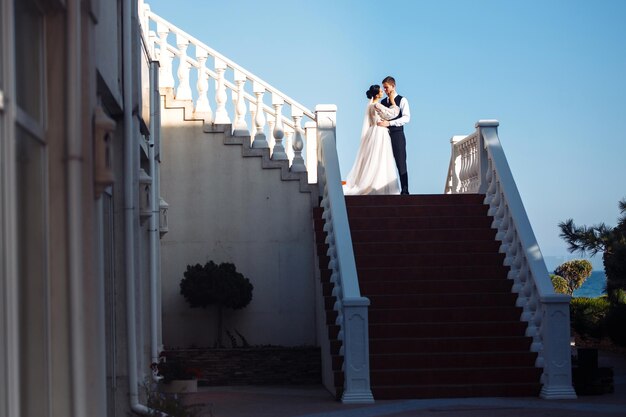 A noiva e o noivo nos degraus da escada Casal elegante e elegante se divertem na escada