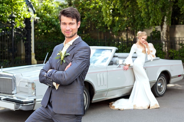 Foto a noiva e o noivo perto de carro retrô. casamento. retrato do noivo de perto