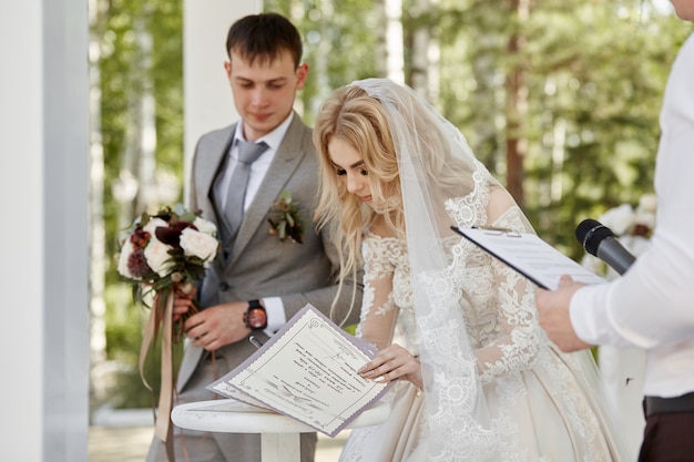 Foto a noiva e o noivo registram seu casamento. casamento na natureza