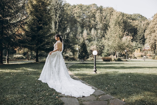 a noiva em um lindo vestido branco fica no meio de uma floresta verde