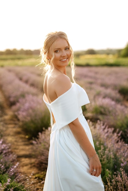 A noiva em um vestido branco caminha no campo de lavanda