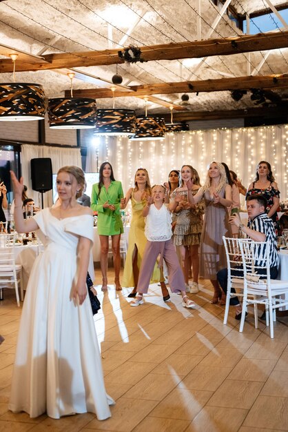 A noiva em um vestido branco joga um buquê de casamento