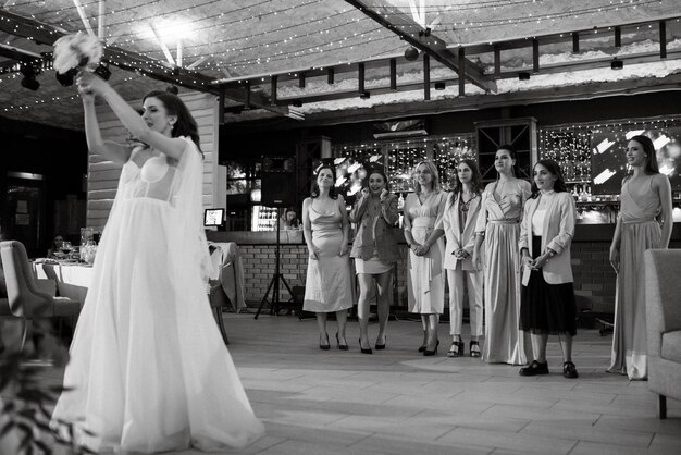 A noiva em um vestido branco joga um buquê de casamento