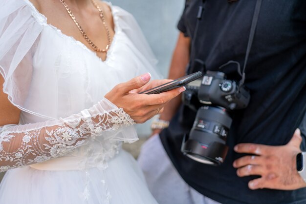 A noiva em um vestido branco tem um smartphone na mão.