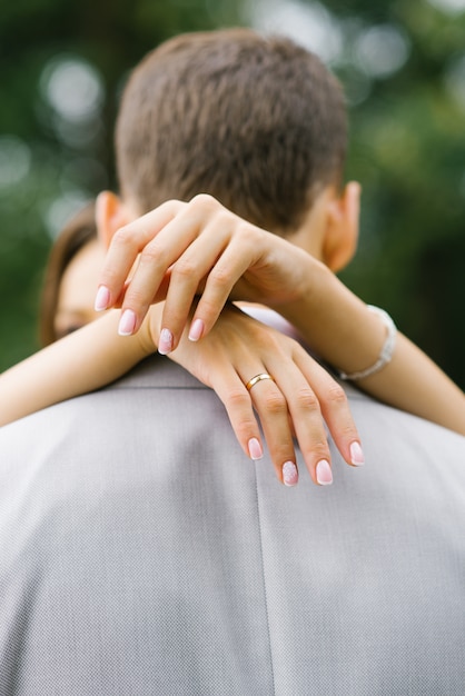 A noiva entrega um abraço ao marido em volta do pescoço. Aliança no dedo dela. O conceito de amor e confiança.