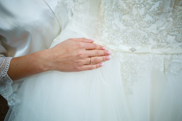 A noiva segura nas mãos um lindo vestido de noiva