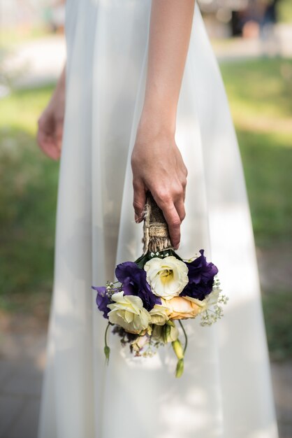 A noiva segura um buquê de casamento com flores roxas