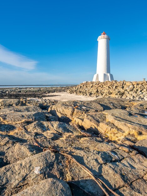 A nova torre ativa do farol de Akranes na península final na cidade sob o céu azul Islândia