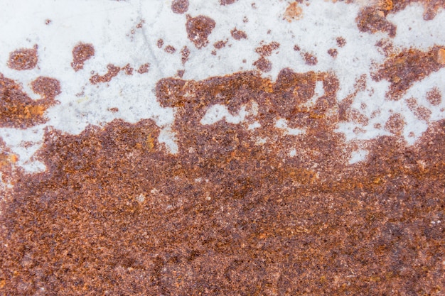A oxidação de Brown mancha a textura da pintura branca velha na parede oxidada do metal. Fundo de metal enferrujado.
