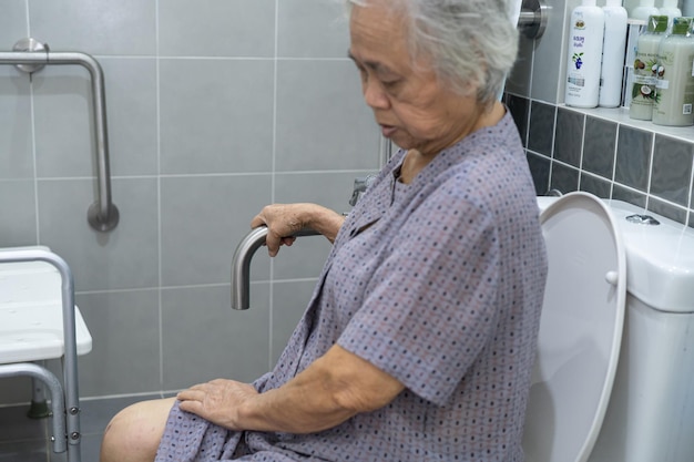 A paciente idosa asiática ou idosa usa a segurança do banheiro do banheiro na enfermaria do hospital de enfermagem, conceito médico forte e saudável.