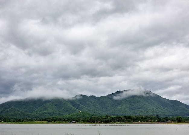 Foto a paisagem da montanha e do reservatório em nuvens nimbus no fundo do céu