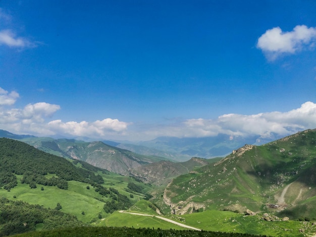 A paisagem do Aktoprak verde passa no Cáucaso a estrada e as montanhas sob nuvens cinzentas Rússia