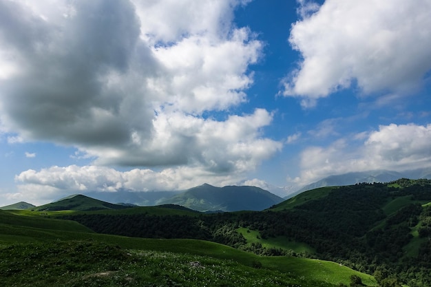 A paisagem do Aktoprak verde passa no Cáucaso a estrada e as montanhas sob nuvens cinzentas