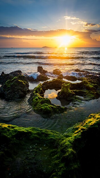 A paisagem do pôr do sol nas rochas da praia em primeiro plano