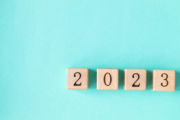A palavra 2023 é feita de blocos de madeira no fundo turquesa Feliz Ano Novo