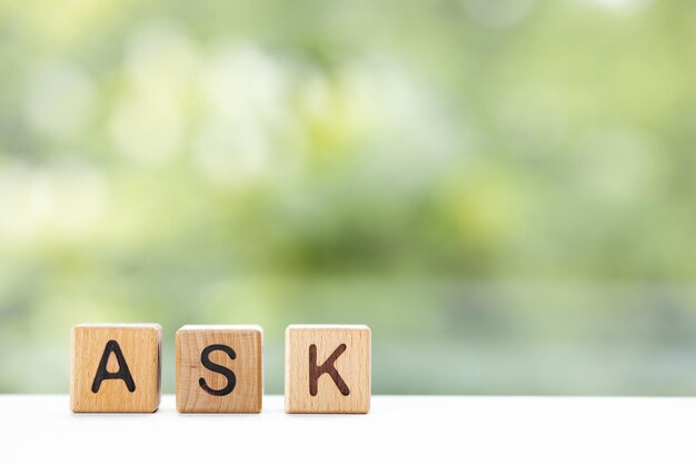 A palavra ASK está escrita em cubos de madeira em um fundo verde de verão Closeup de elementos de madeira