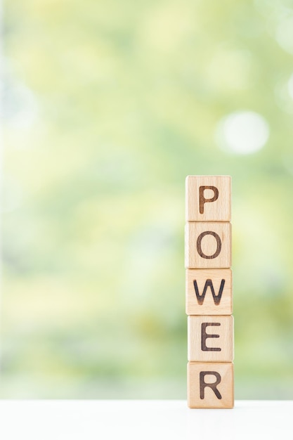 A palavra de poder está escrita em cubos de madeira em um fundo verde de verão Closeup de elementos de madeira