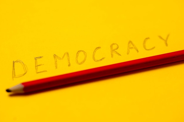 A palavra democracia escrita a lápis sobre um fundo amarelo