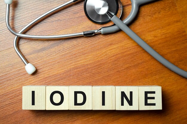 A palavra IODO é escrita em cubos de madeira perto de um estetoscópio em um fundo de madeira Conceito médico