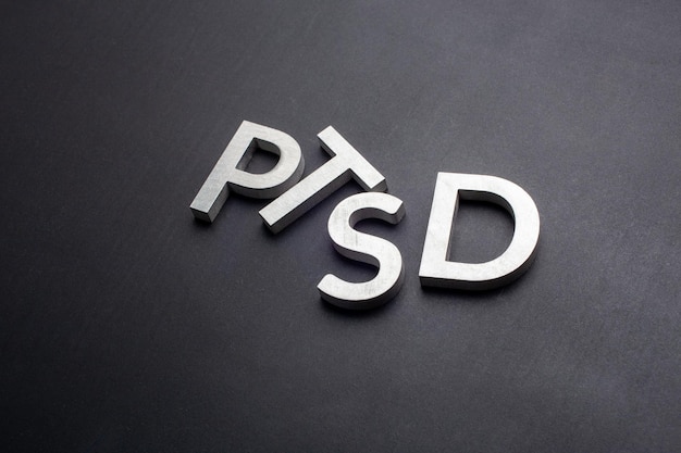 A palavra PTSD colocada com letras de metal prateado em fundo preto liso