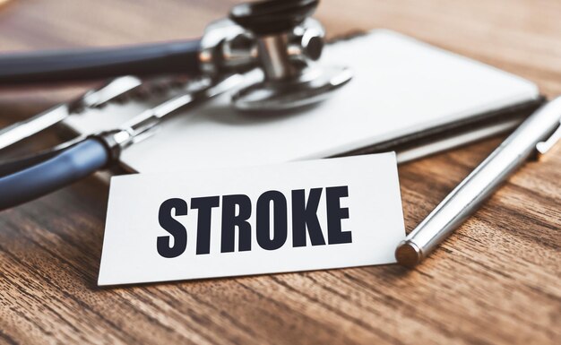 A palavra STROKE está escrita em um cartão sobre uma mesa de madeira com formação médica Conceito de medicina