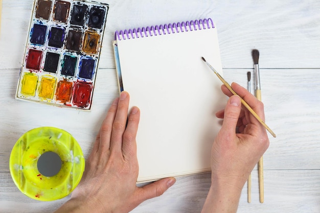 A paleta de pintura das mãos do artista escova cores diferentes A garota está desenhando As ferramentas do artista para arte e inspiração reais Vista superior
