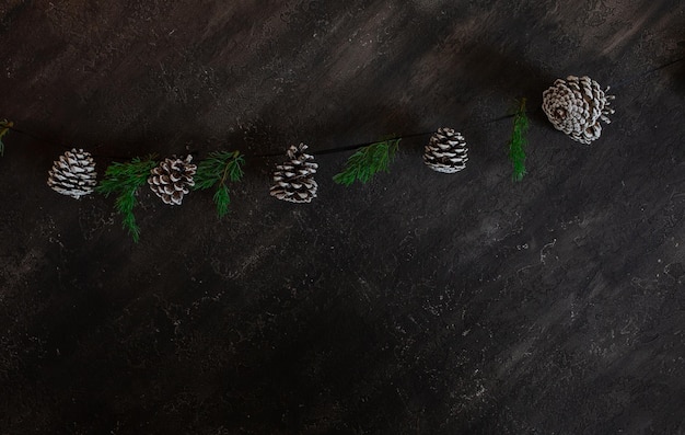 A parede preta na sala do loft é decorada para o Ano Novo e o Natal Lindos galhos de árvores de Natal e lanternas quentes de guirlandas, cones e bolas Conceito de ano novo Espaço de cópia plana leiga