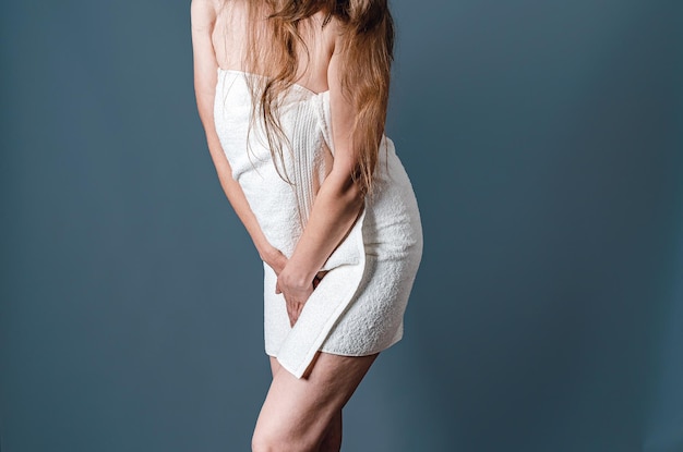 A parte do meio de uma mulher com dor vaginal é dobrada Corpo feminino em uma toalha branca Ombros nus