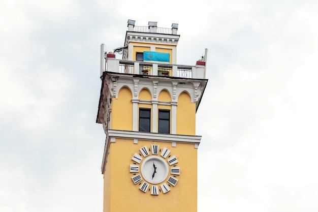 A parte superior da torre de incêndio em Khmelnytskyi na Rua Proskurivska com um relógio e a bandeira da Ucrânia