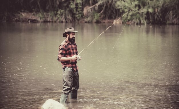 A pesca masculina no lago relaxa no ambiente natural bom lucro continua pescando o homem relaxando e