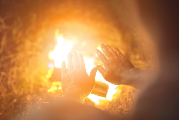 Foto a pessoa aquecendo as mãos acima da fogueira. noite noite