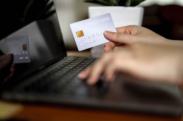 A pessoa possui um cartão de crédito e está preenchendo as informações do cartão de crédito para pagar produtos online. Os cartões de crédito podem pagar por produtos e serviços tanto na loja quanto em compras online.