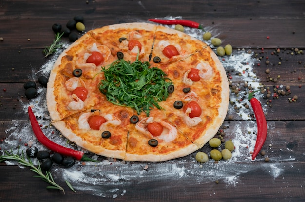 A pizza italiana maravilhosa e saboroso encontra-se em um fundo escuro das placas de madeira.