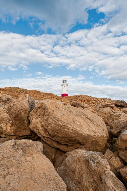 Foto a ponta de um farol em rochas contra o céu nublado