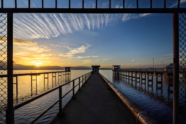 A ponte para o lago com o céu do nascer do sol