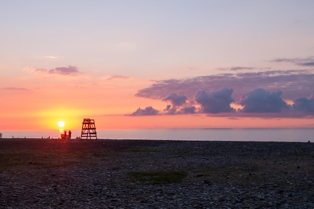 A praia ao pôr-do-sol, pessoas à distância.