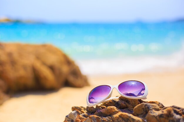 A praia com óculos de sol na rocha