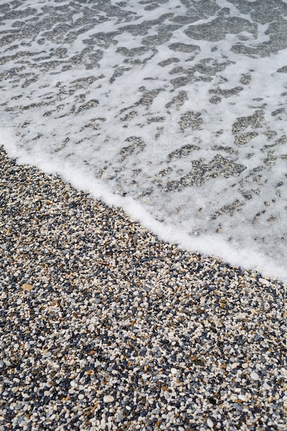 A praia da costa mediterrânea com ondas de água azul. Brisa do mar de verão