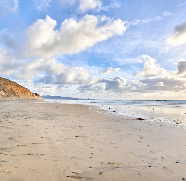 A praia de Torrey Pines San Diego Califórnia Paisagem de praia vazia mostrando a costa Pegadas de caminhantes permanecem na areia enquanto o sol começa a se pôr e as nuvens vêm sobre o céu