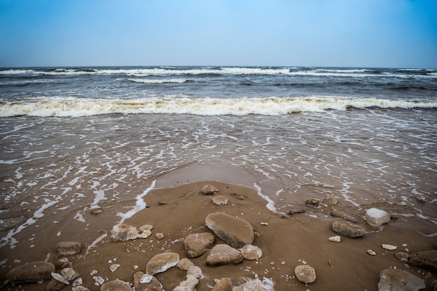 A praia fria de inverno do mar báltico tem neve e há ondas fortes no mar, em saulkrasti, na letônia