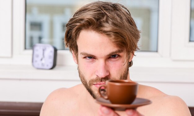 A primeira hora da manhã A melhor hora para tomar sua xícara de café Todas as manhãs com seu café Homem barbudo e bonito macho segura a xícara de café Homem de aparência atraente aprecia café quente fresco