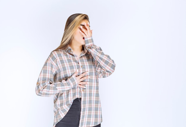 A rapariga com uma camisa xadrez parece pálida e com sono