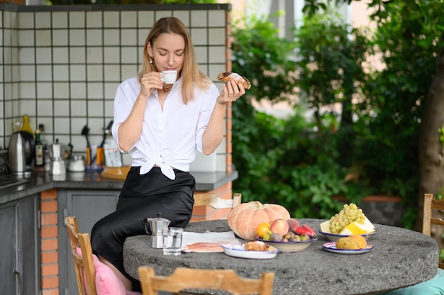 A rapariga cozinhava o pequeno-almoço e bebe café com sobremesa