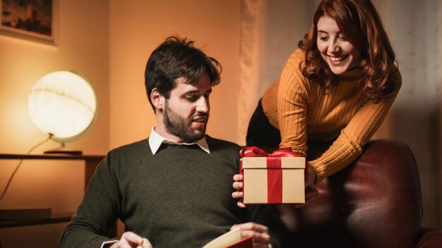 Foto a rapariga dá uma caixa de presentes de são valentim ao namorado.